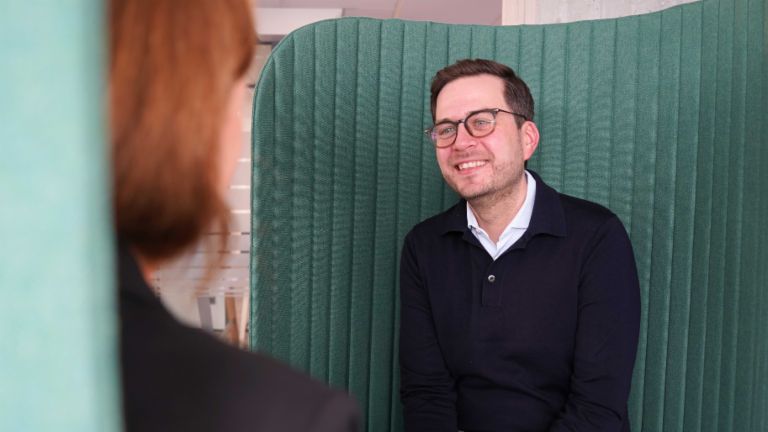 A man in an office environment in an interview situation.