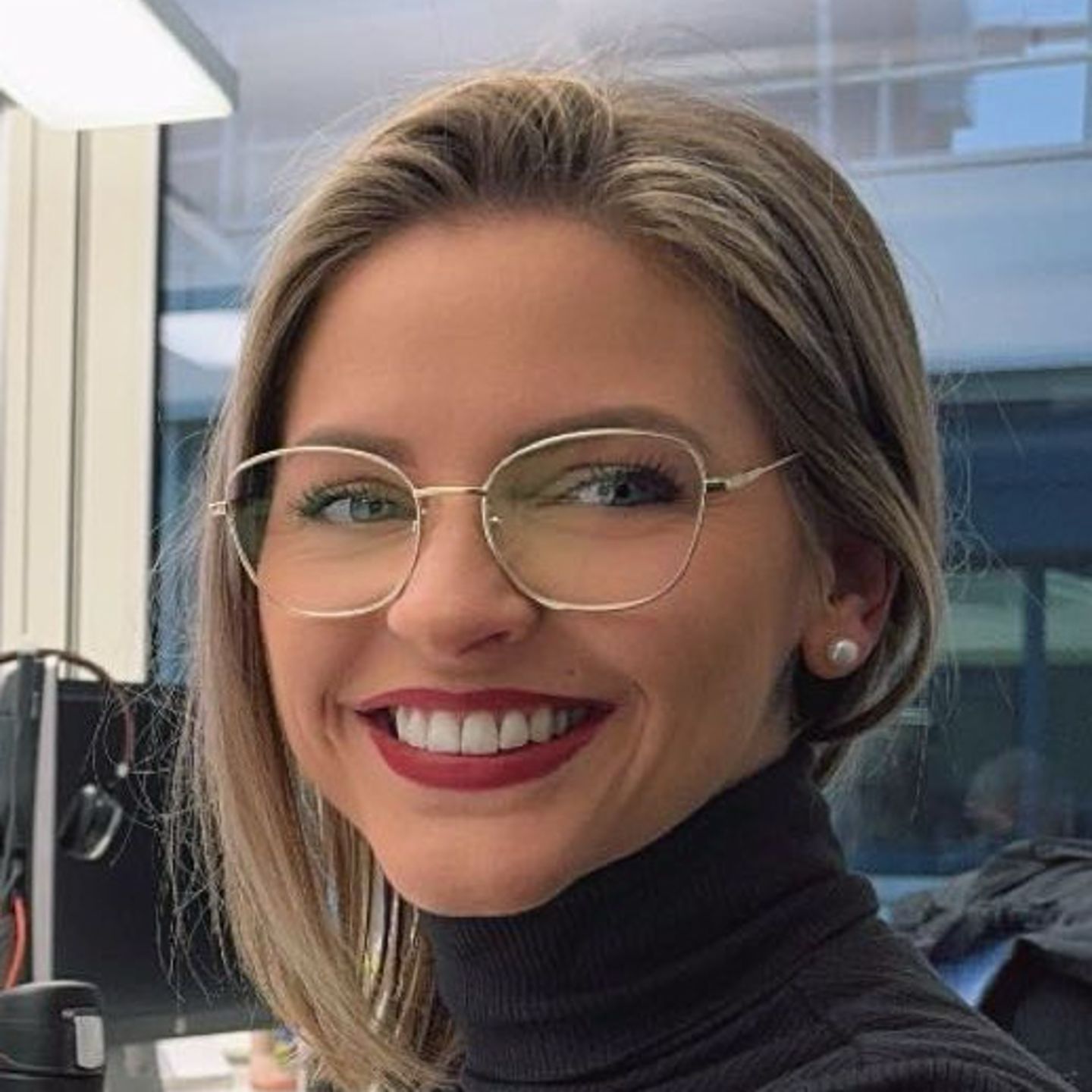 Η Genny Bollinger, Ειδικός Αναδιάρθρωσης Χρέους στην EOS στην Ελβετία, κάθεται στο γραφείο της με ένα γκρι πουλόβερ με ζιβάγκο και χαμογελά στην κάμερα.