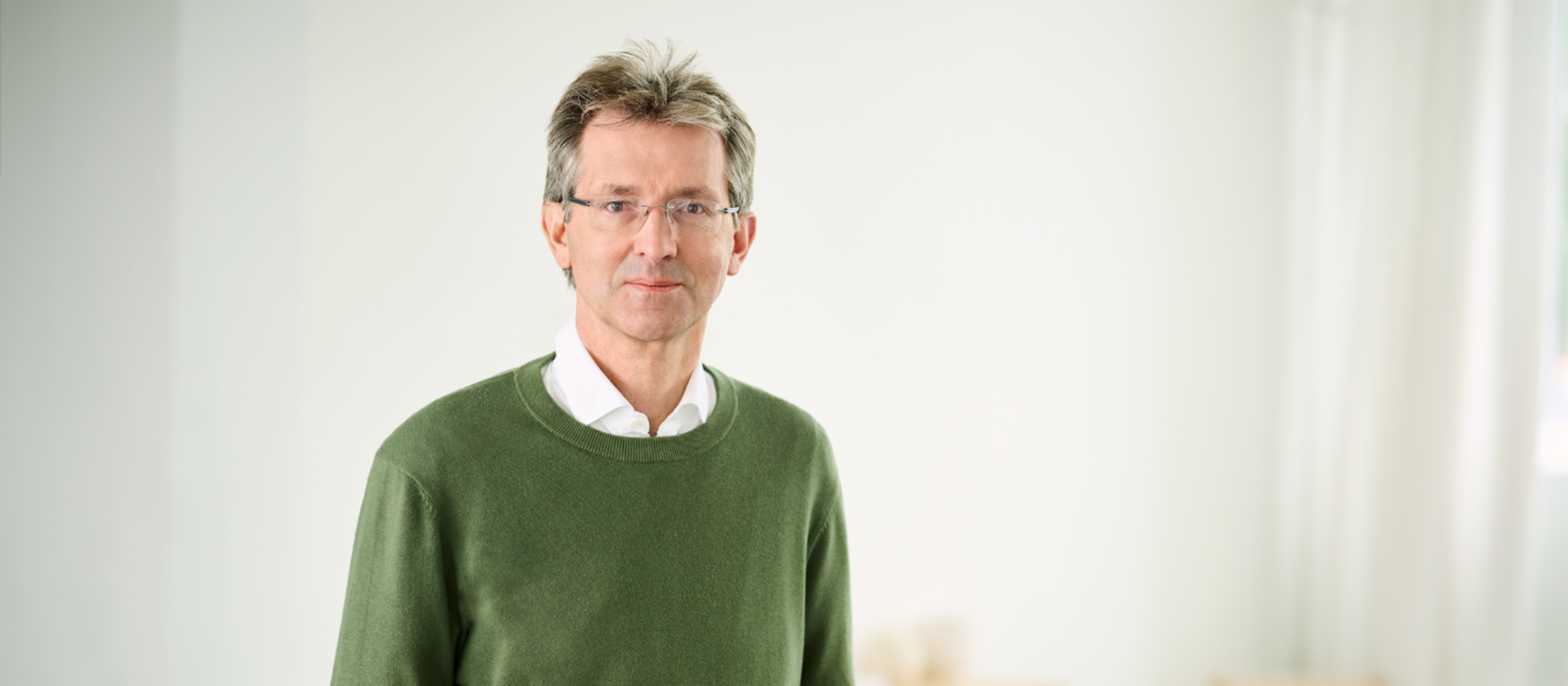 Justus Hecking-Veltman, Οικονομικός Διευθυντής, με πράσινο πουλόβερ και λευκό πουκάμισο, όρθιος σε ένα φωτεινό δωμάτιο.