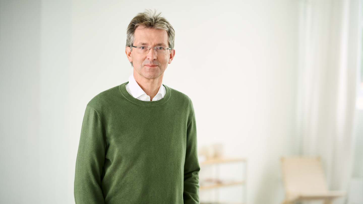 Justus Hecking-Veltman, Οικονομικός Διευθυντής, με πράσινο πουλόβερ και λευκό πουκάμισο, όρθιος σε ένα φωτεινό δωμάτιο.