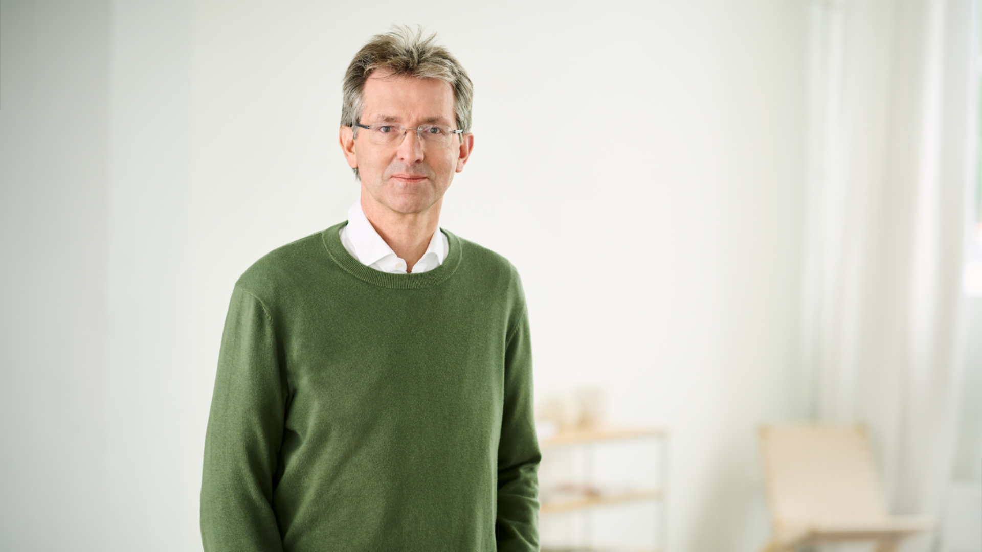 Justus Hecking-Veltman, Οικονομικός Διευθυντής, με πράσινο πουλόβερ και λευκό πουκάμισο, όρθιος σε ένα φωτεινό δωμάτιο.