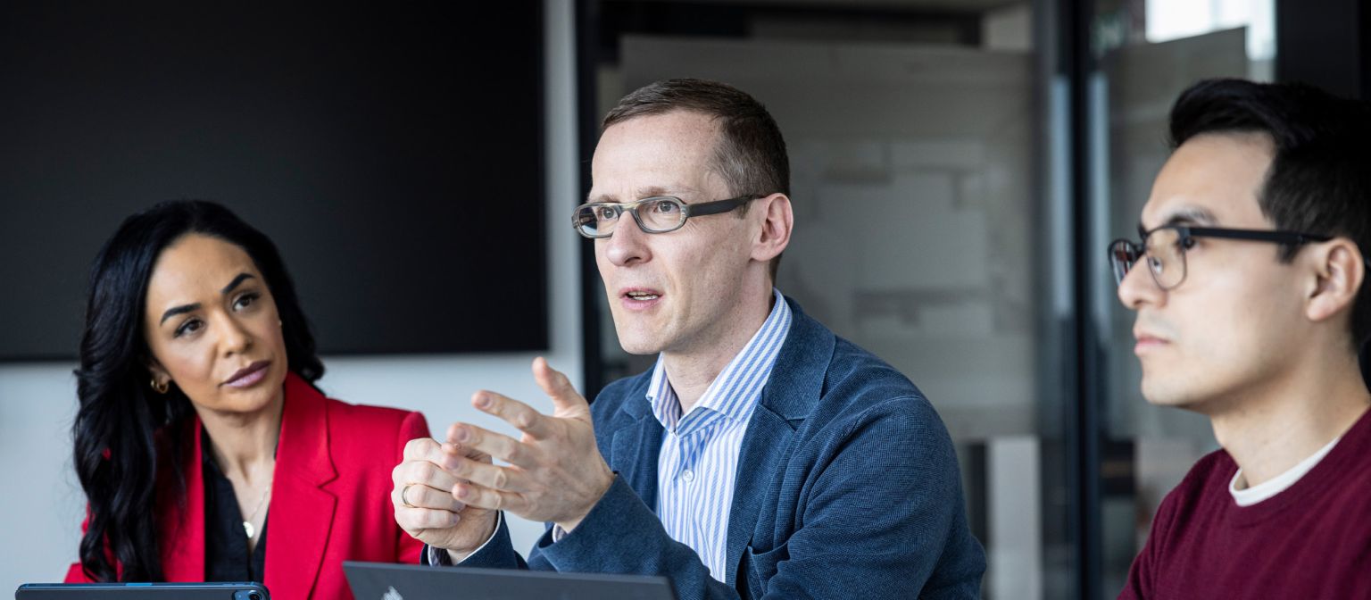 Τρία άτομα συνομιλούν σε ένα γραφείο.