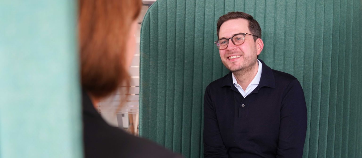 A man in an office environment in an interview situation.