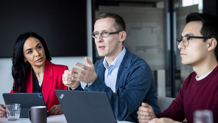 Τρία άτομα συνομιλούν σε ένα γραφείο.